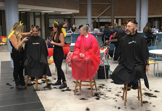 Faculty and staff getting their hair shaved off as part of a fundraising activity
