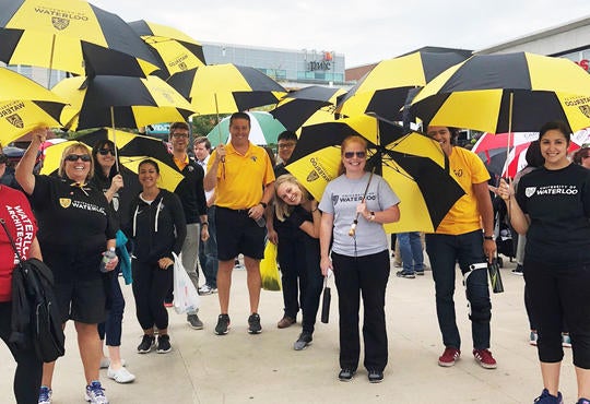 Group of staff and students under gold and black umbrellas