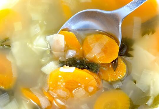 A close up of vegetable soup with a spoon