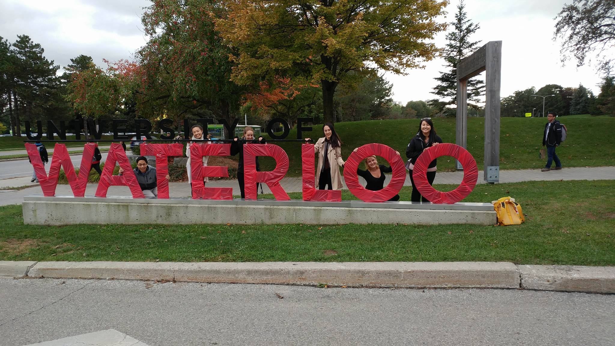 volunteers and a red university of waterloo sign 