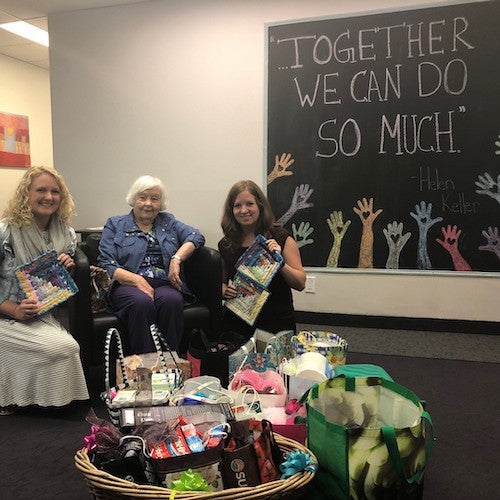 Women sit in front of a chalkboard that says "together we can do so much."