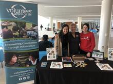 Three volunteers behind an event table with VAC swag.