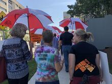 VAC volunteers walking with umbrellas.