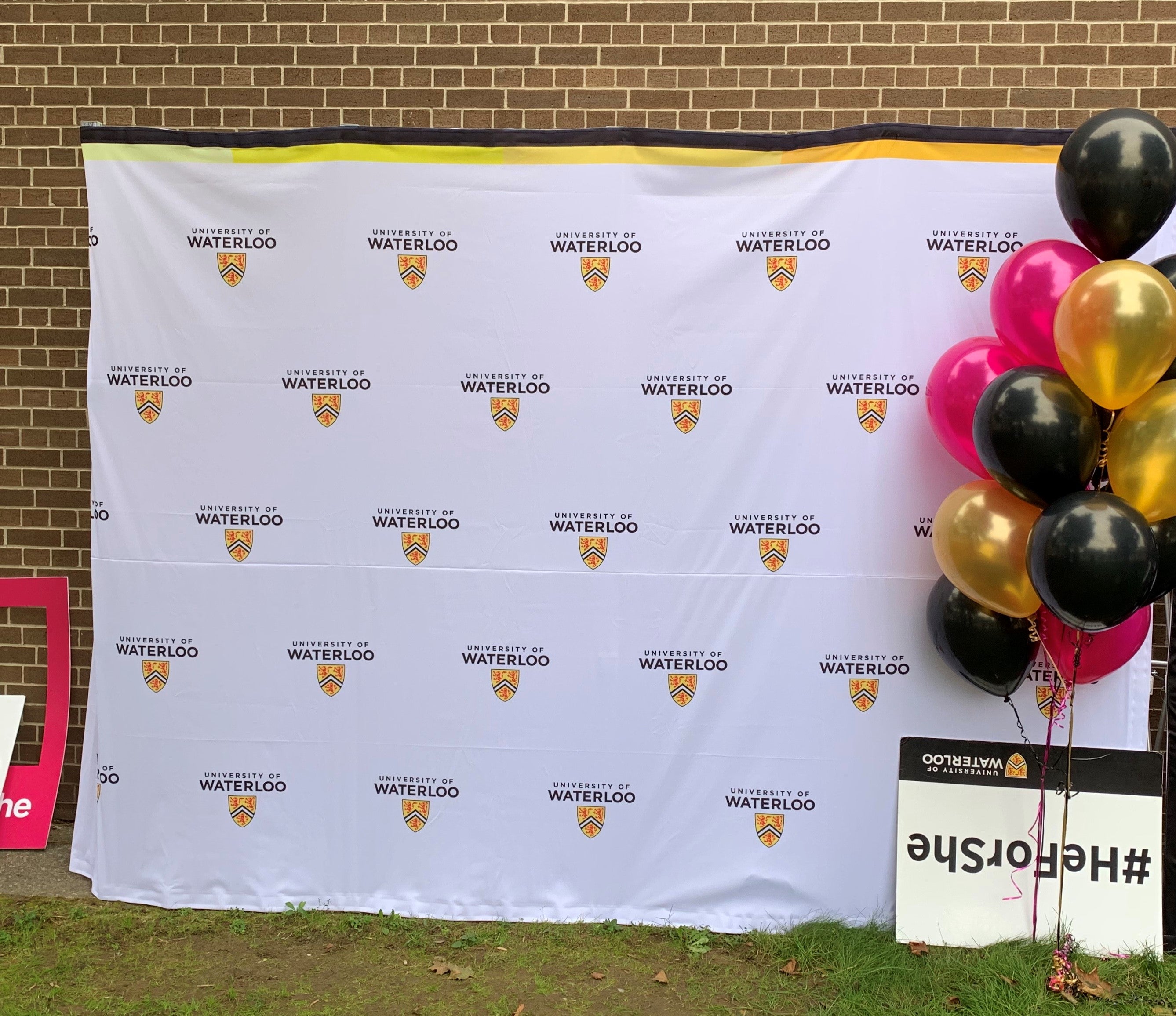 White backdrop banner featuring a repeating pattern of the “University of Waterloo” name and crest logo.