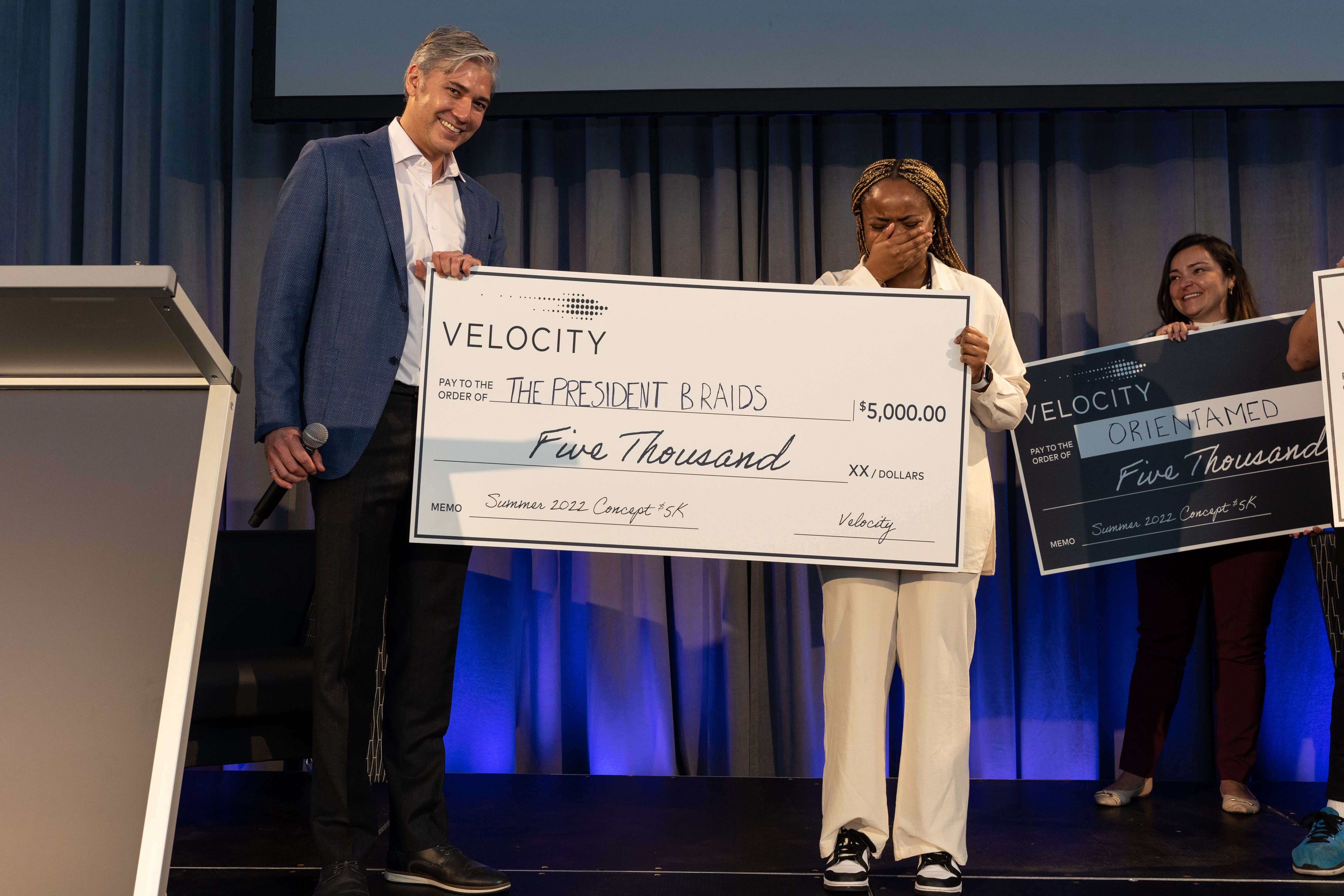 The President Braids company receives a large cheque from Velocity for the Summer 2022 Concept 5K.