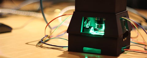 VIP Lab with a gadget radiating green light with wires around it 