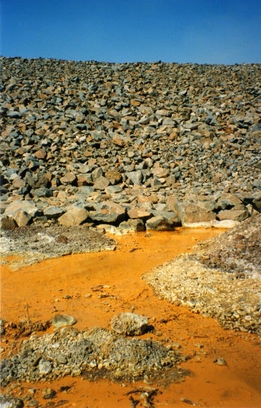 Mine effluent discharging from the bottom of a waste rock pile