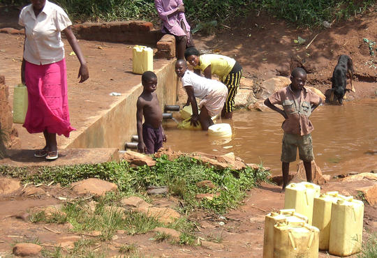 African children and women carrying water in Uganda 