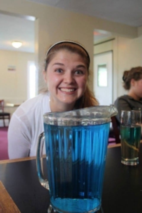 smiling student above pitcher of blue liquid.