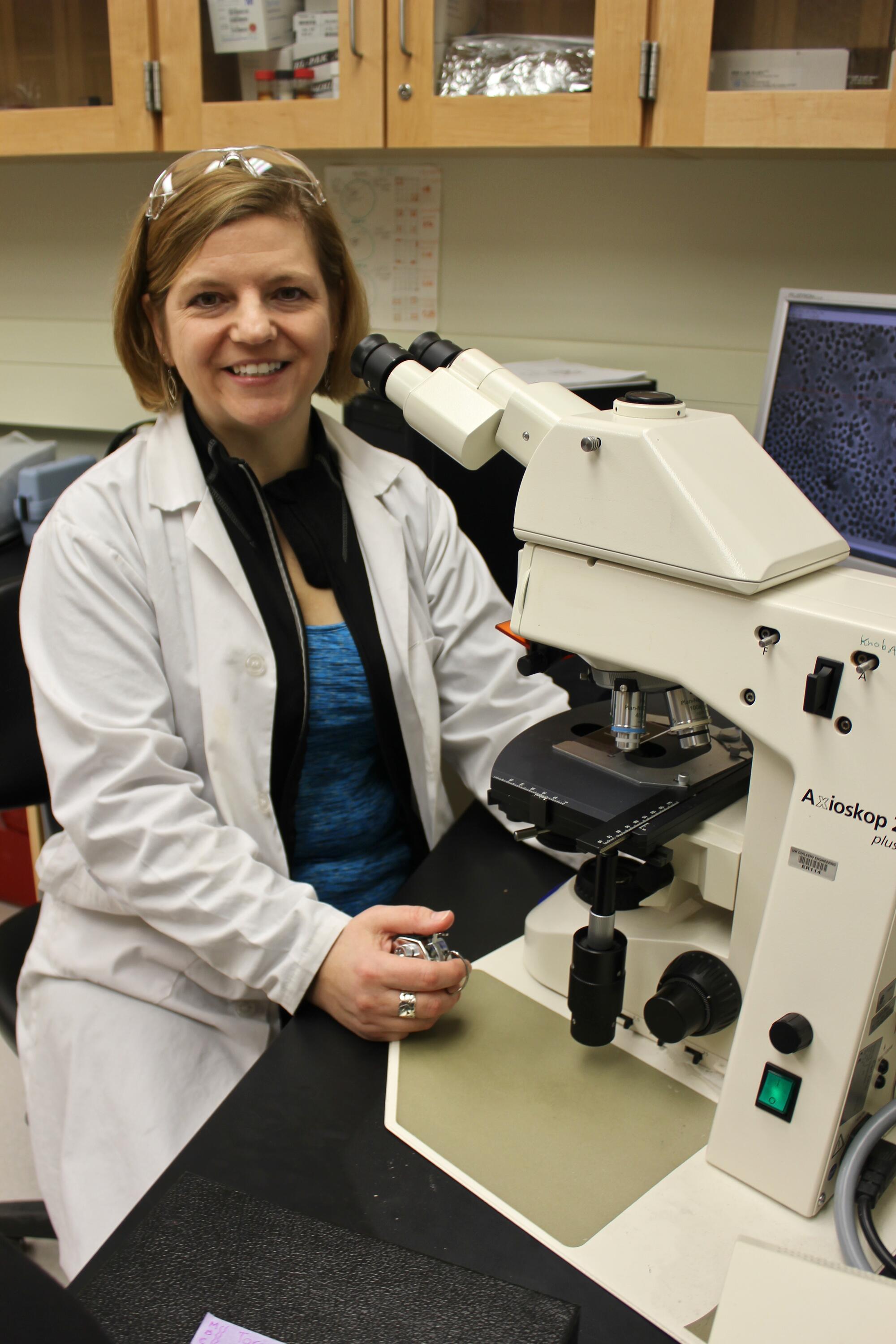 Professor Monica Emelko seated at a microscope.