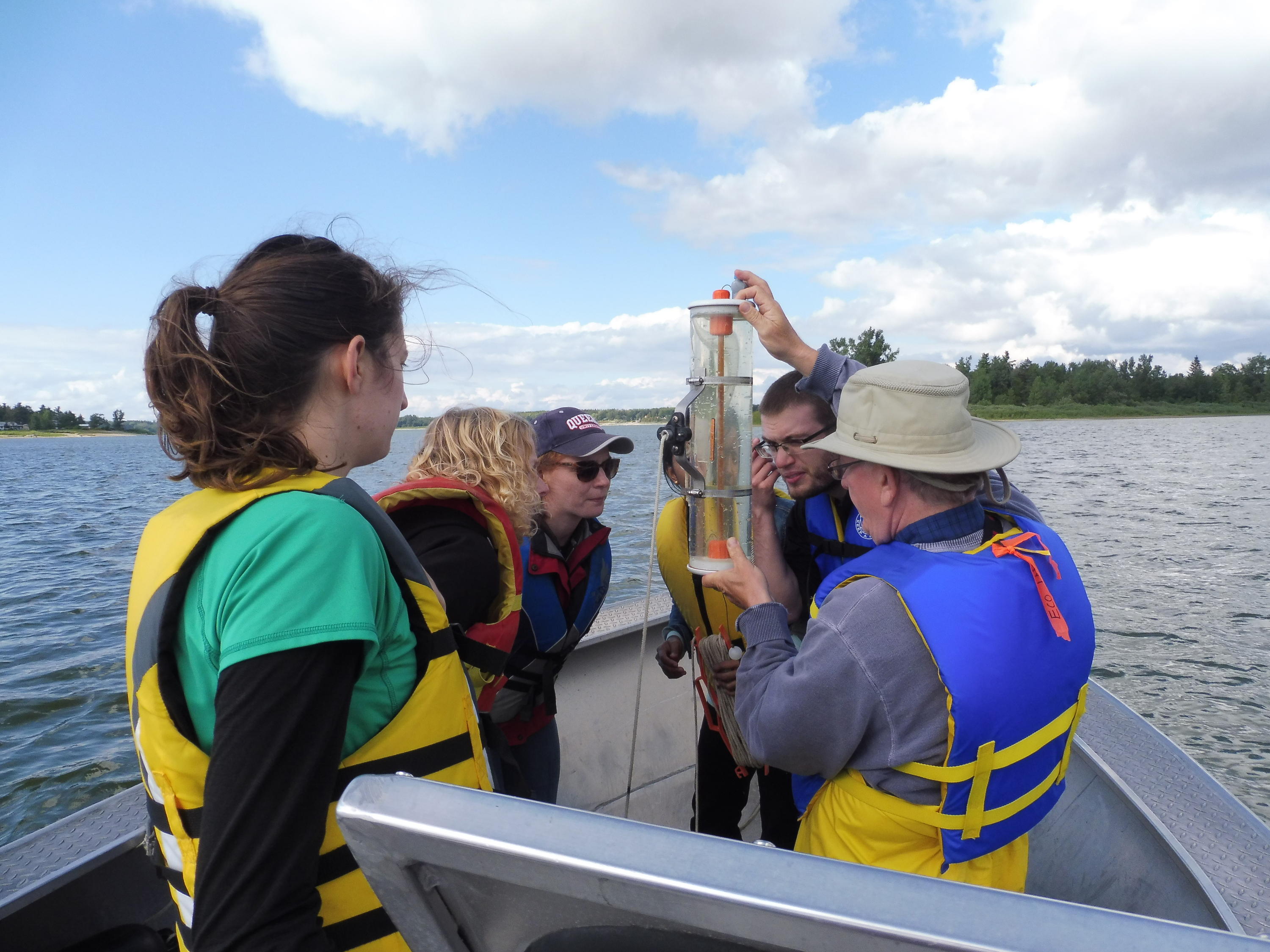 students on boat studying water sample