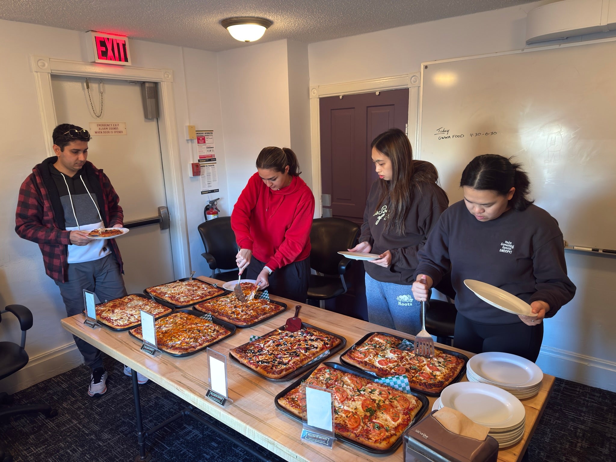 Attendees gather at the Halloween trivia night, getting pizza
