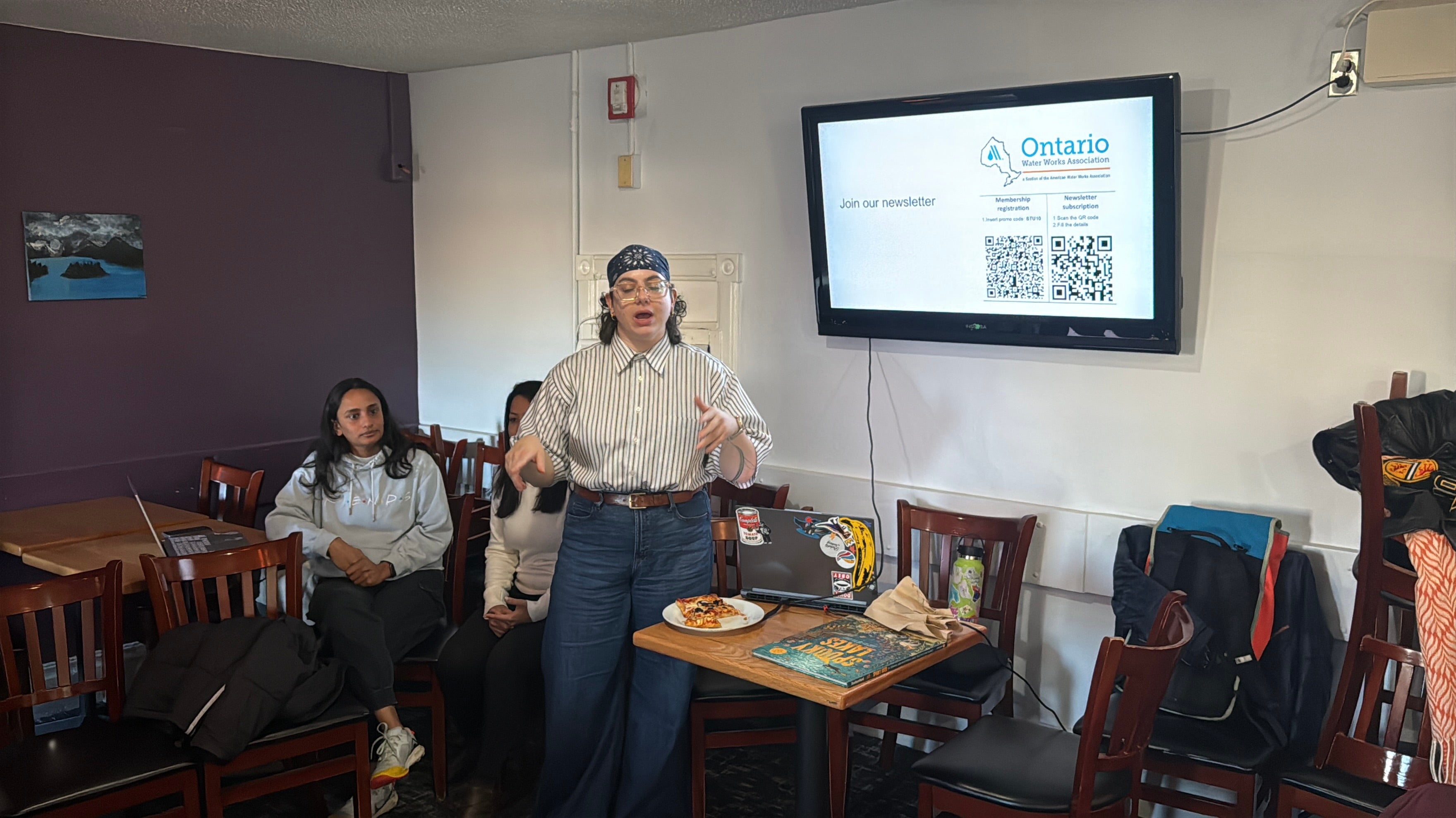 Trivia host stands in front of the screen encouraging attendees to register for the newsletter