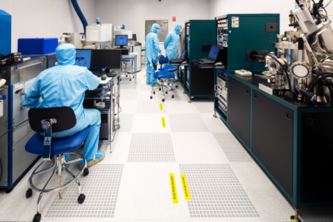 Three people in protective suits inside a lab at the Quantum nano fabrication and characterization facility (QNFCF)