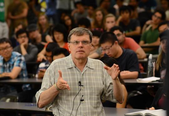 Larry Smith speaking in a background of students 