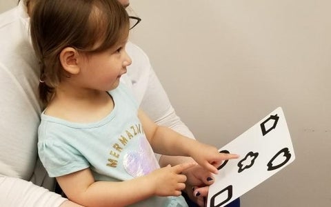 Child having her vision tested with picture card