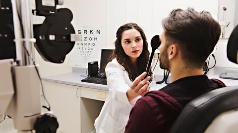 Optometrist conducting visual acuity test with eye occluder 