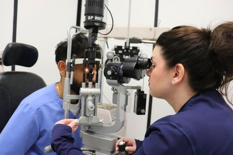 Dr. Chelsea Bray performing an eye exam using a slit lamp on a student.