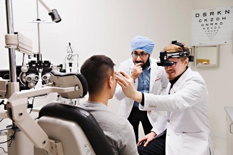 two student optometrists examine a patient.