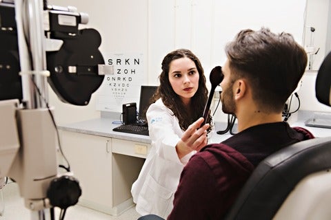 Optometrist conducting visual acuity test with eye occluder 