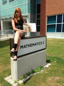 female identfying person sitting on mathematics 3 building sign