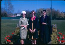 graduation photo with three people standing side by side smiling