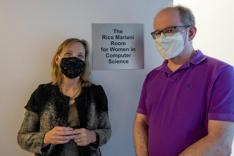 woman and man stand on either side of a room sign