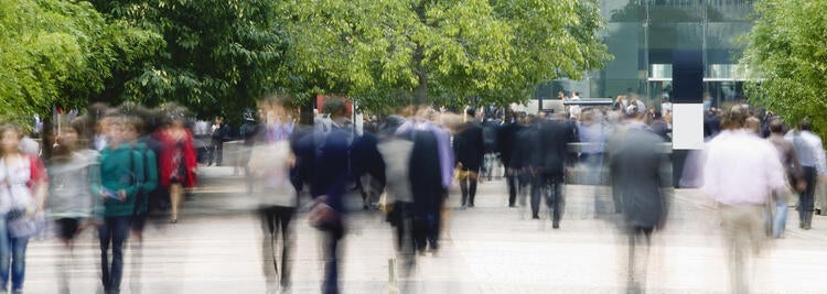 Blurred image of people walking in front of builings