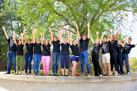 A group of students with her hands in the air 