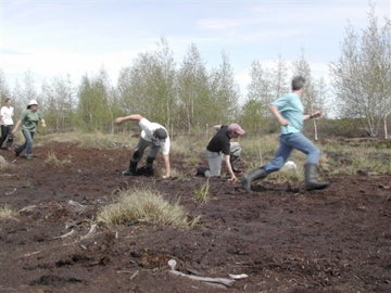 Three men running in a peat field.