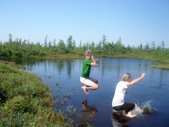 Two students jumping into a peatland pool.