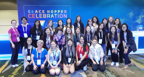 A group of attendees infront of the Grace Hopper banner in 2019.