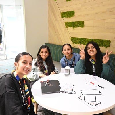 4 girls sitting around a round table smiling at the camera