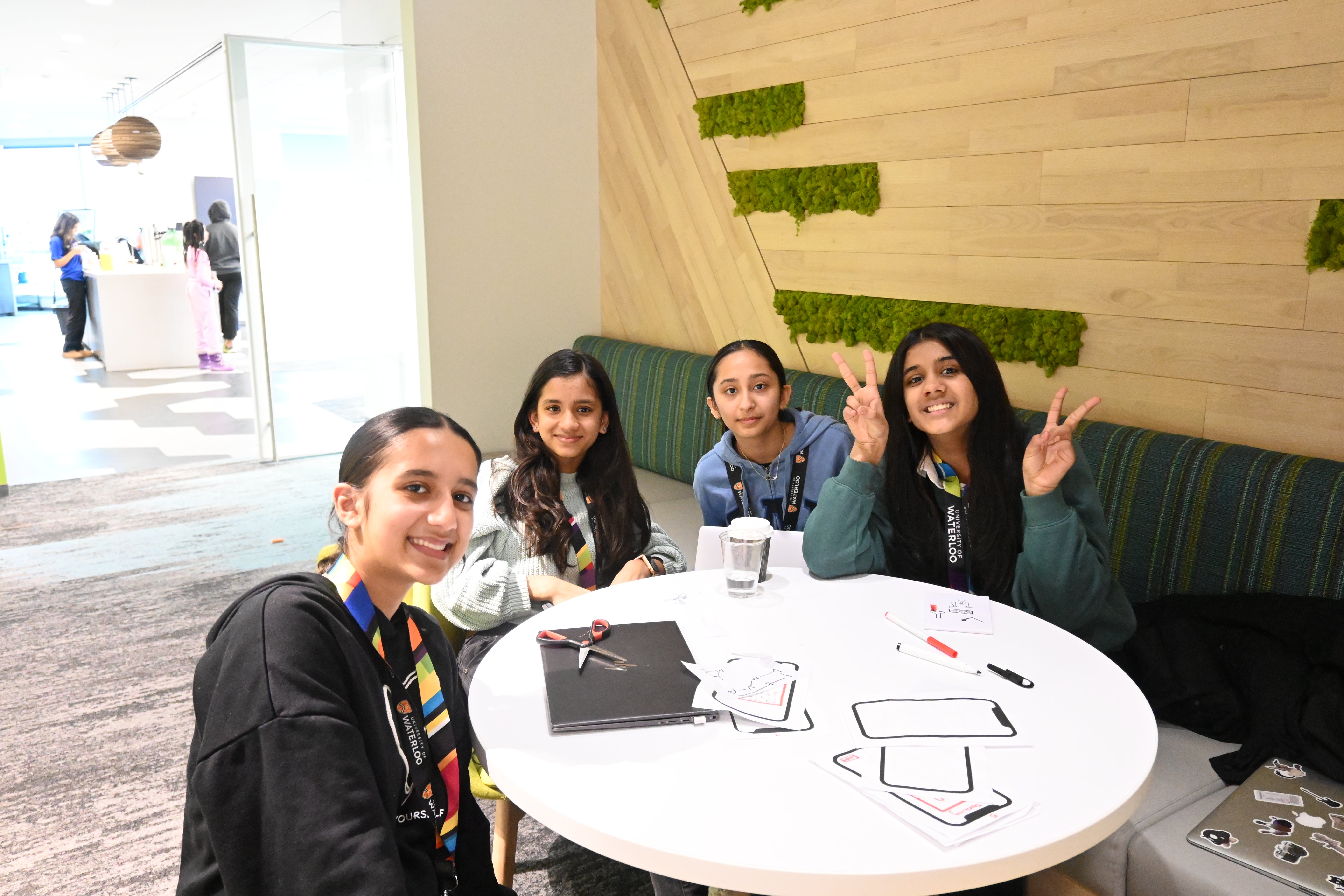 4 girls sitting around a round table smiling at the camera