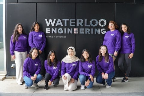 Students in purple shirts standing in front of engineering sign