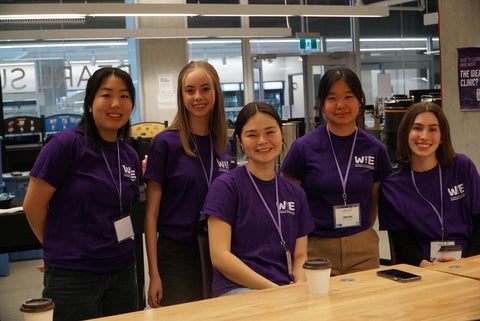 Five female students in purple tshirts smiling at the camera