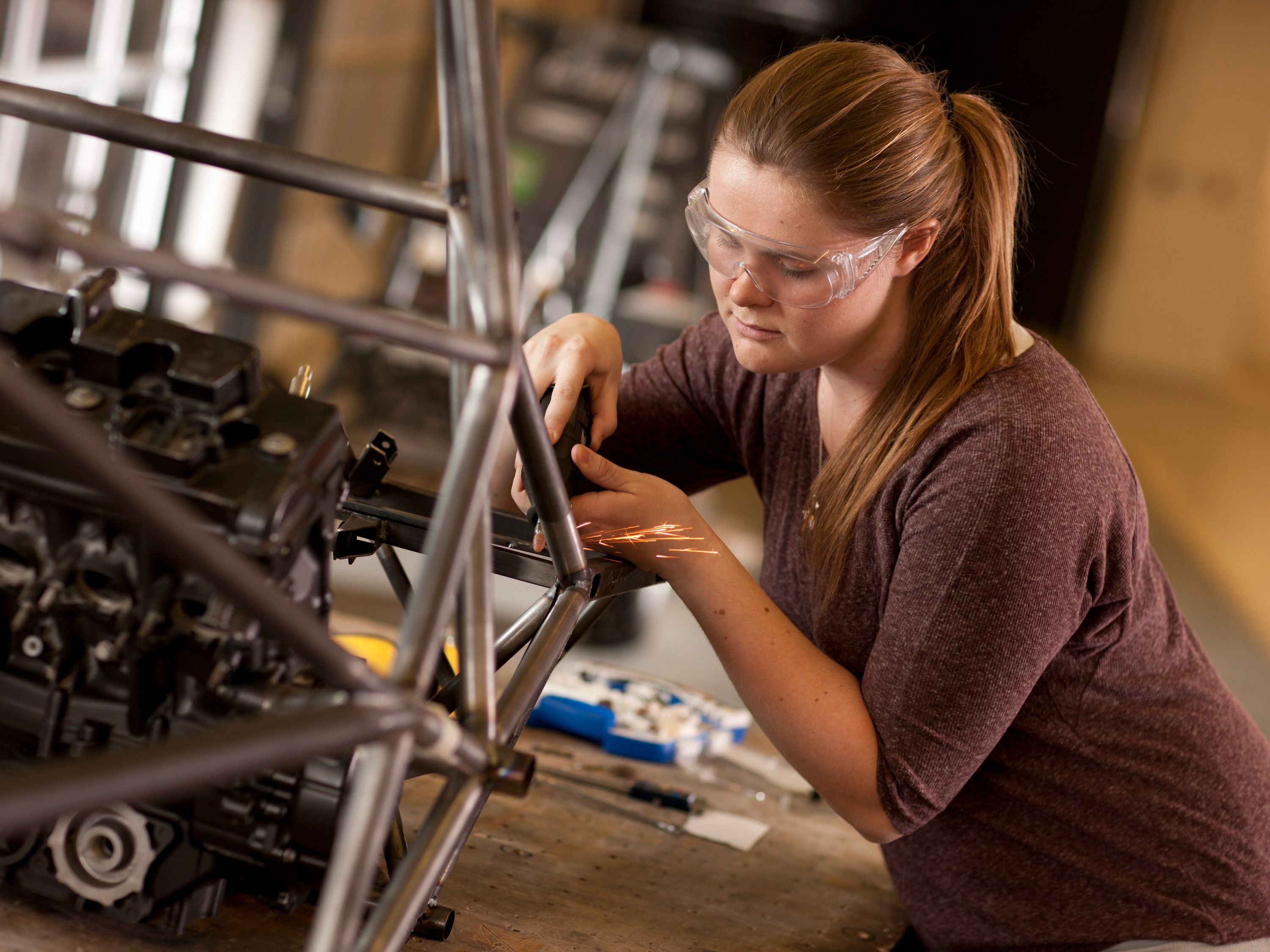 Women in engineering using an angle grinder on a steel frame
