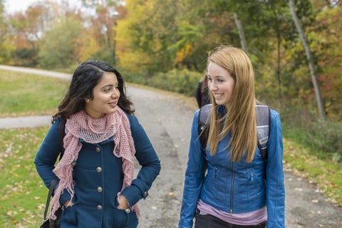 Two female students walking outside in the fall