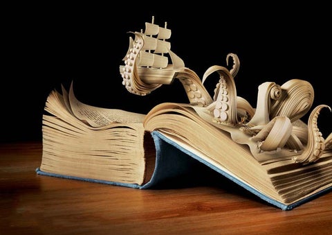A picture of a paper octopus coming out of a book, clutching a paper ship