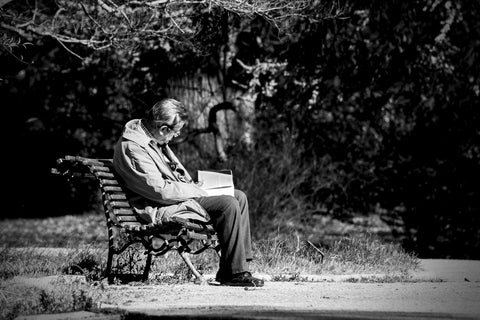 old man reading on a park bench