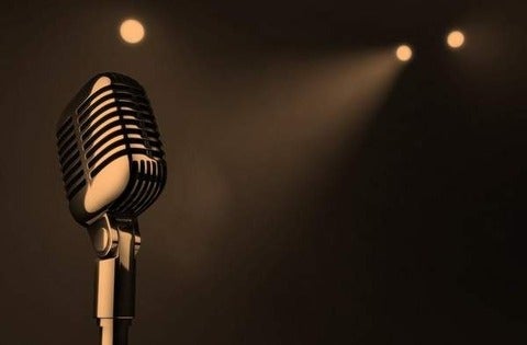 A sepia picture of an old style mic on a dark background with 3 spotlights