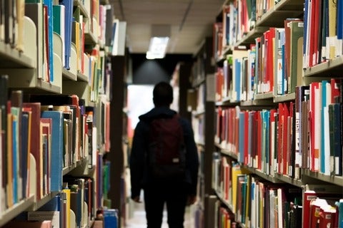 student walking between book shelves
