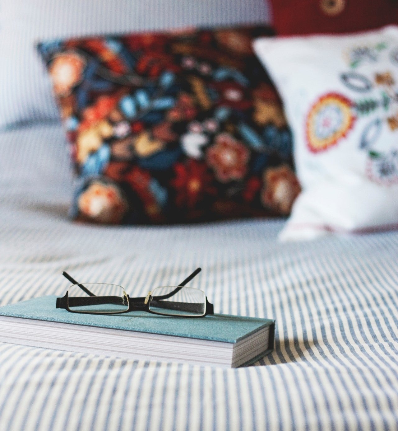 Book and pair of glasses on a bed