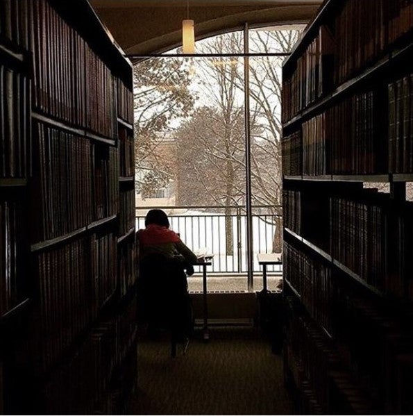 student studying in library beside window