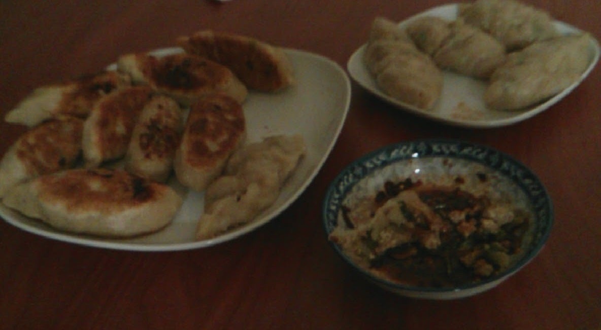 A plate of pan fried dumplings and a plate of steamed dumplings with a small plate of mix spicy suaces!