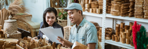 Young craftsman presents paper craft design to a businesswoman, showcasing youth-led social entrepreneurship.