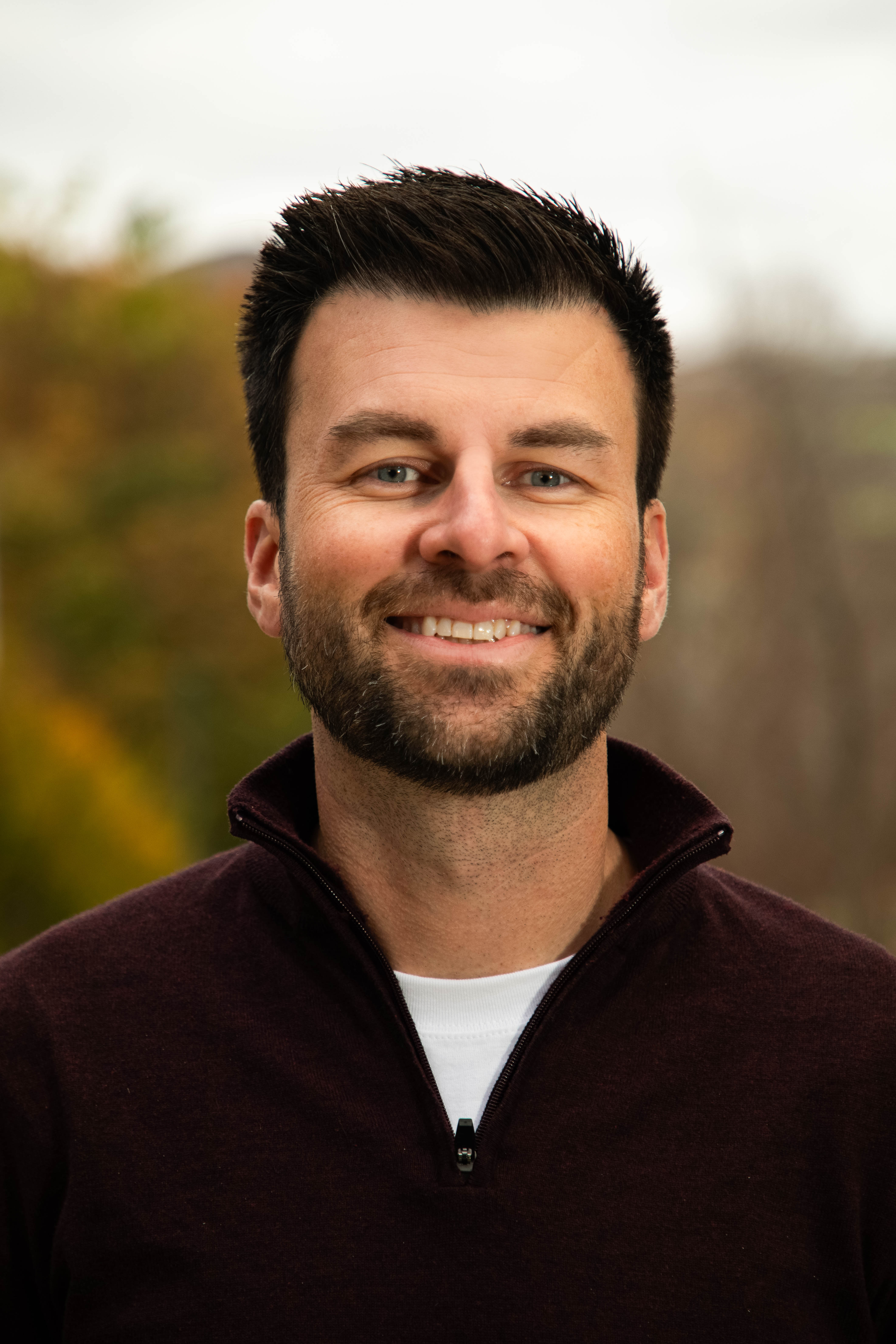 Photo of Mike Ronchka set against a blurred autumn outdoor background.